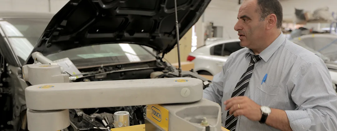 A BMW X5 on the alignment bench inside the workshop, bonnet up, being measured.